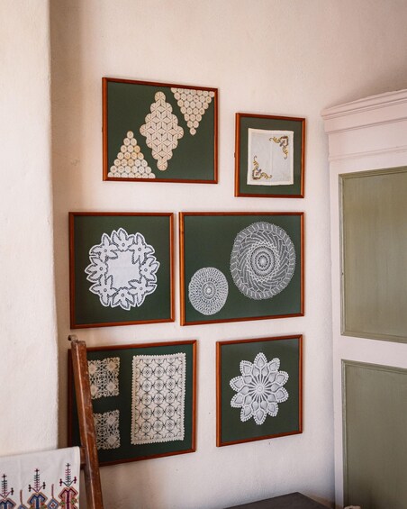 A wall with six framed lace patterns. 4