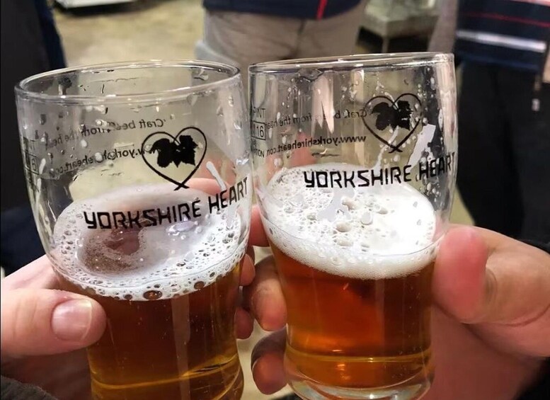 Two glasses of Yorkshire Heart beer held by hands. 5