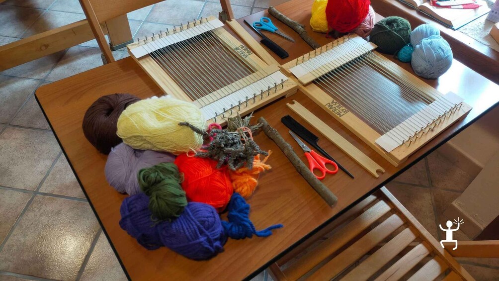 A table with two weaving looms, colorful yarns, scissors, and a comb. 5