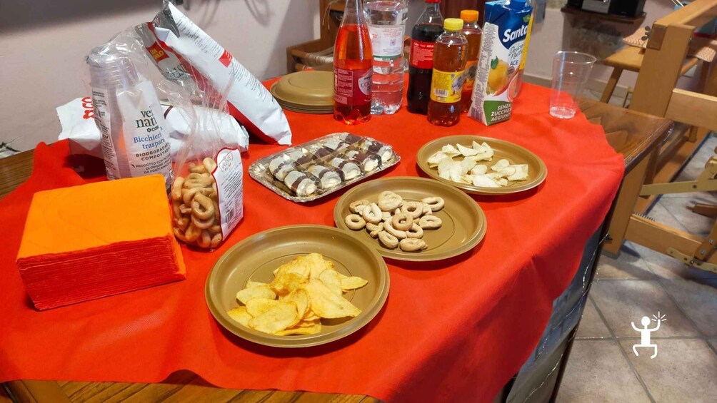 A table with various food items, including chips, biscuits, and bottles of beverages. 3
