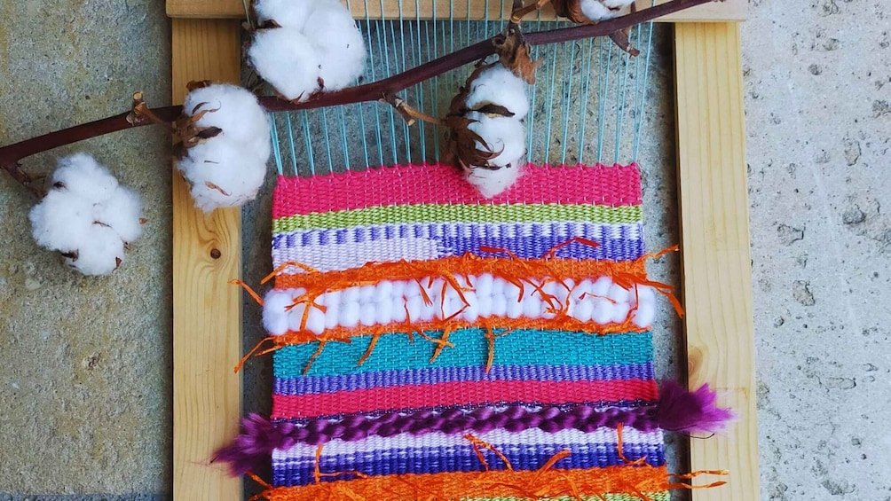 A colorful woven textile with cotton branches. 3