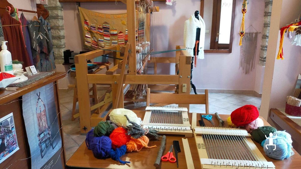 A knitting station with various yarns, knitting needles, and a wooden loom. 4