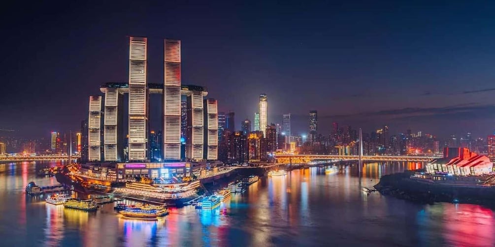A cityscape at night with illuminated buildings, a river, and a bridge. 1
