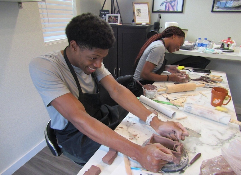 Two individuals engaged in a culinary activity, using a rolling pin and various kitchen tools on a marble countertop. 1