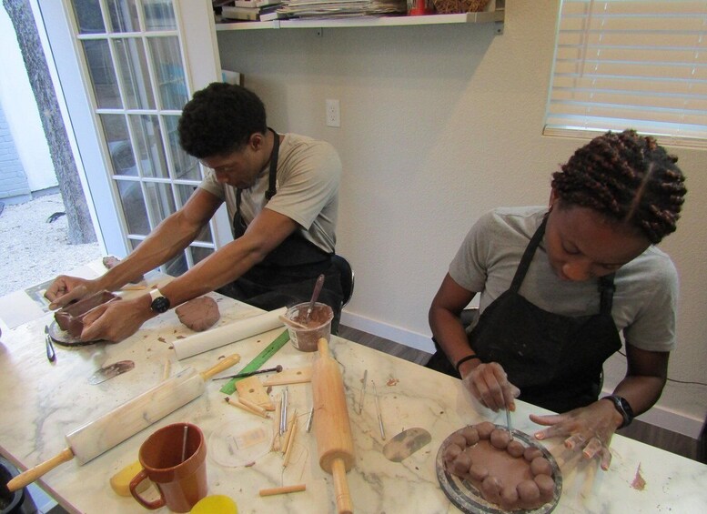Two people working with dough on a marble countertop, surrounded by baking tools and ingredients. 5