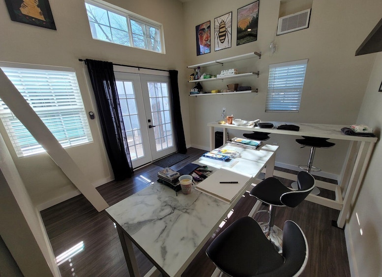 A modern kitchen with a marble countertop, black chairs, and a dining table. 2
