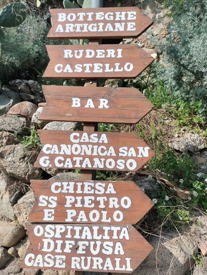 A wooden signpost with multiple directional arrows pointing to various destinations. 2