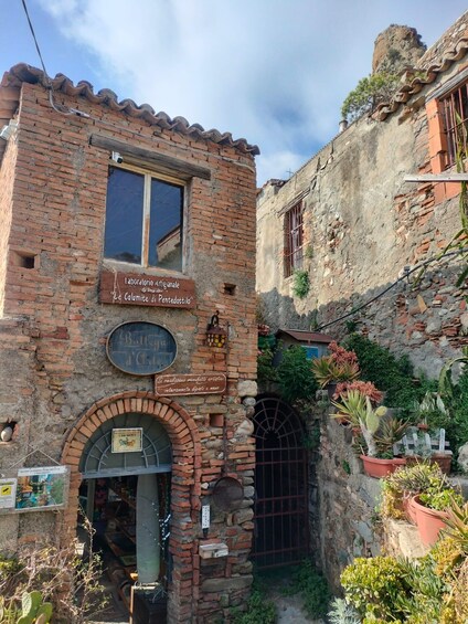 A rustic brick building with a sign for 'Laboratorio Artigianale' and a small shop entrance. 3