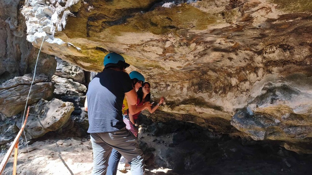 A person guiding a child through a rocky cave. 1