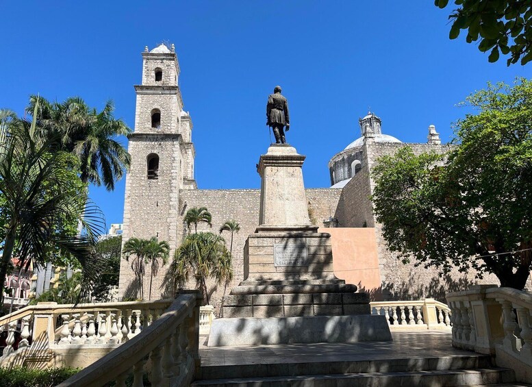 Un bâtiment historique, orné d’une statue et bordé de palmiers, sous un ciel d’un bleu limpide. 4
