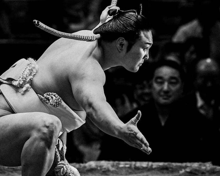 A sumo wrestler in a crouched position, ready to engage in a match. 5