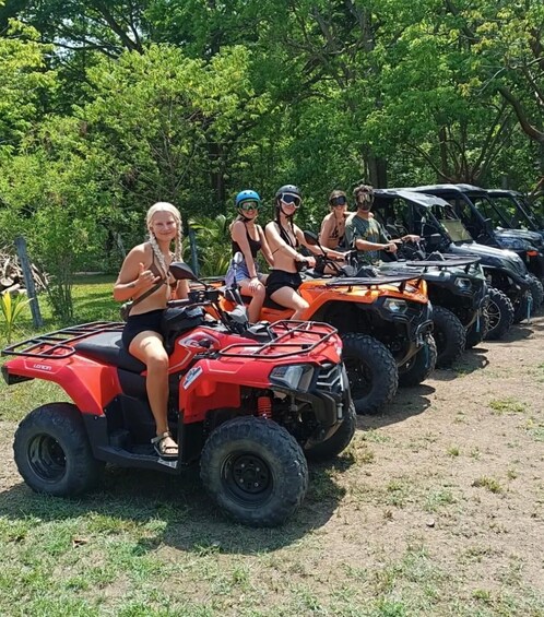 A group of people on ATVs in a line, with trees in the background. 5