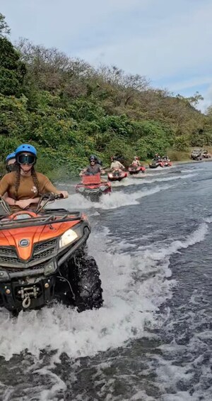 People riding ATVs on a river. 2