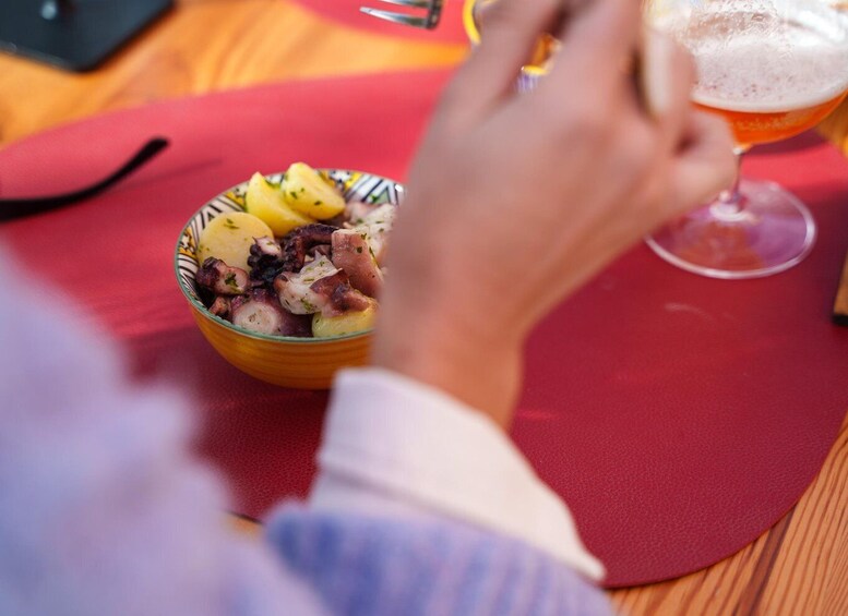 A person holding a glass of beer, with a bowl of food in the foreground. 2