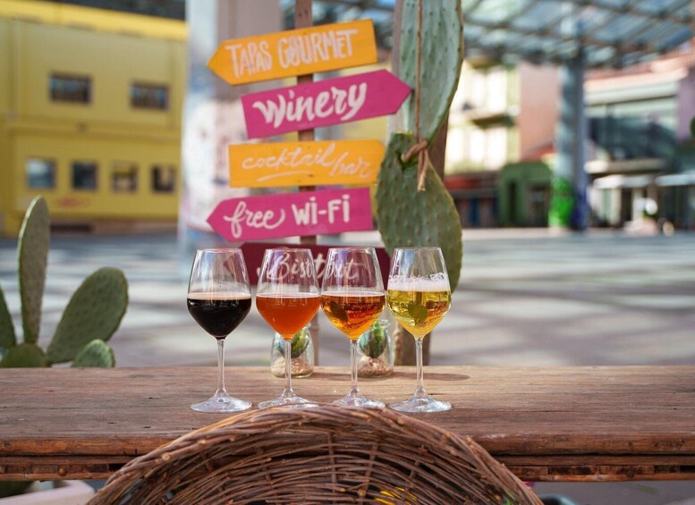 Four glasses of beer on a wooden table with a cactus and a signboard in the background. 4