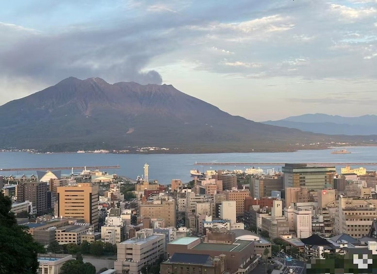 A cityscape with a prominent mountain in the background, a body of water in the foreground, and a bridge connecting two land masses. 3