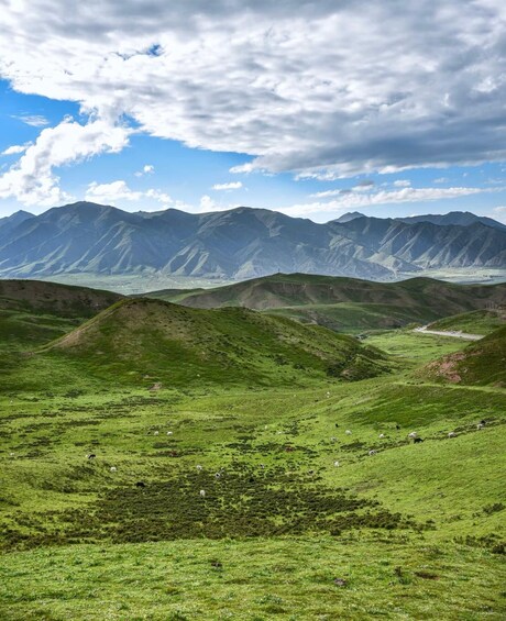 A mountainous landscape with green valleys and a winding road. 2