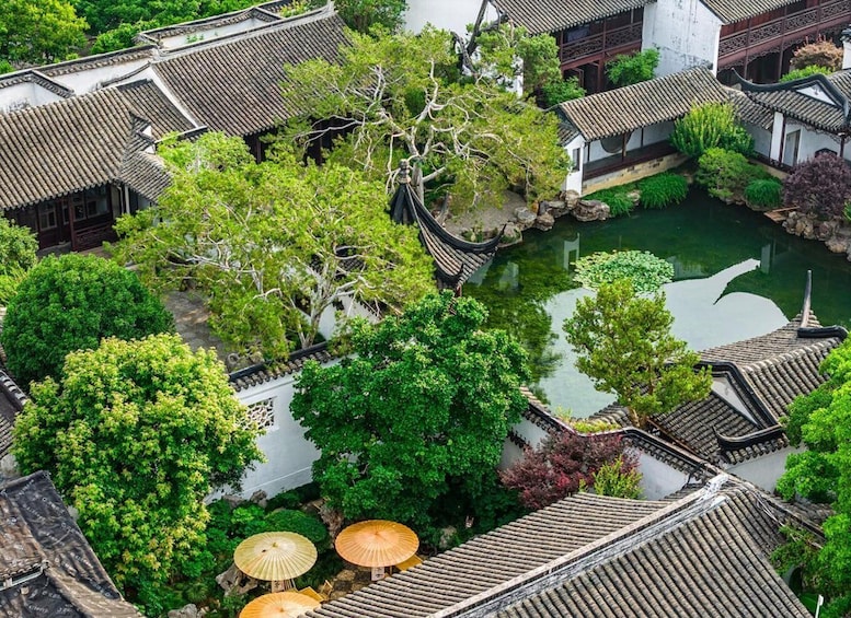 A traditional courtyard with tiled roofs, a pond, and lush greenery. 5