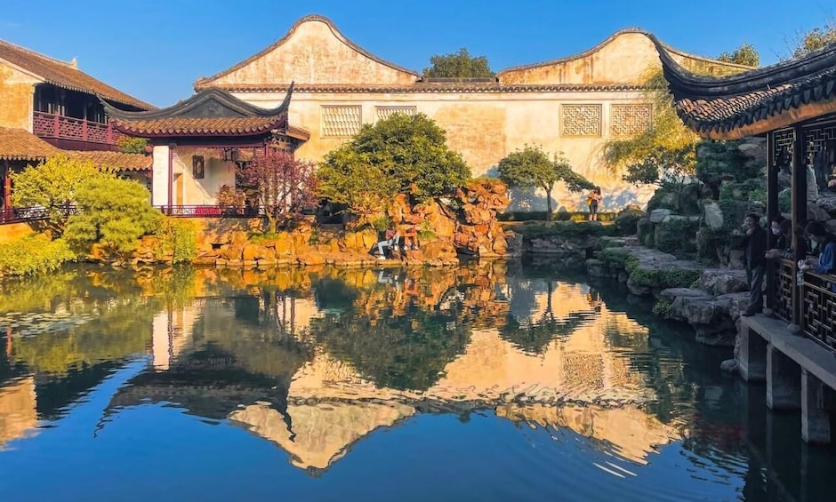 A traditional Chinese courtyard with a pond, reflecting buildings, and a rock formation. 1