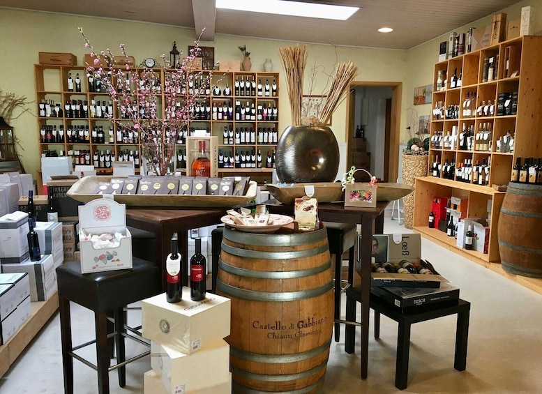 A wine shop with shelves of bottles, a large wooden barrel, and decorative branches. 5
