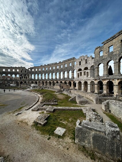 An ancient stone amphitheater with multiple arches and ruins. 1