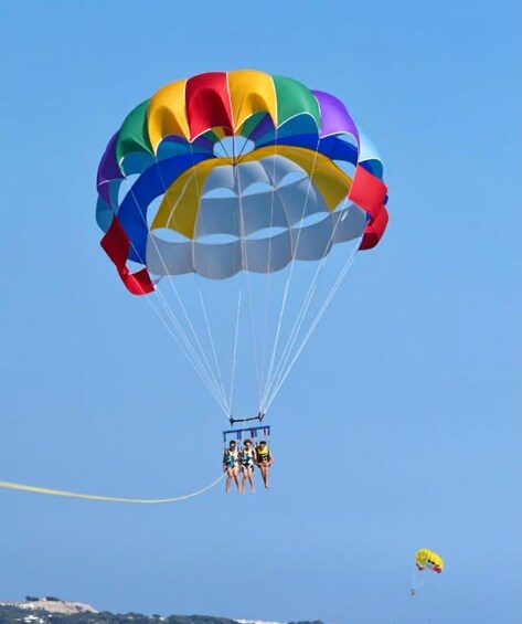 A person parachuting with a colorful canopy, another parachute visible in the distance. 4