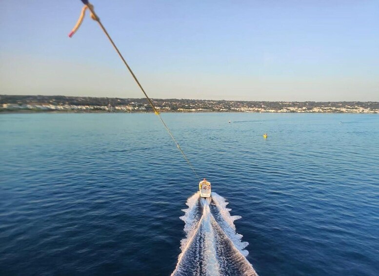 A boat's wake in the water with a fishing rod extended towards the shore. 3