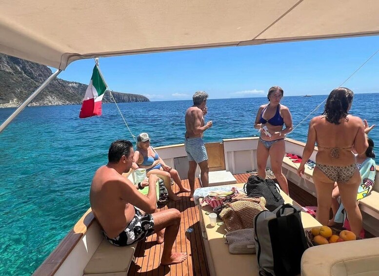 A boat with people on deck, a flag, and clear blue water. 2