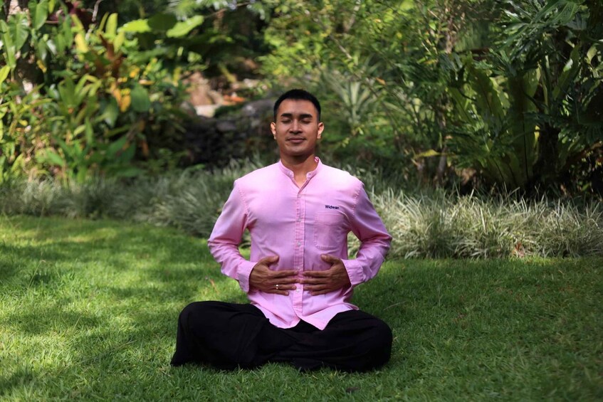 A person sitting on grass in a garden with greenery in the background. 2