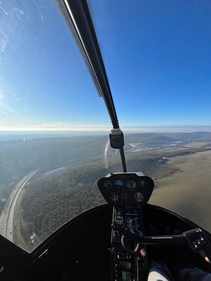 A helicopter cockpit with a clear view of a highway and surrounding landscape. 3