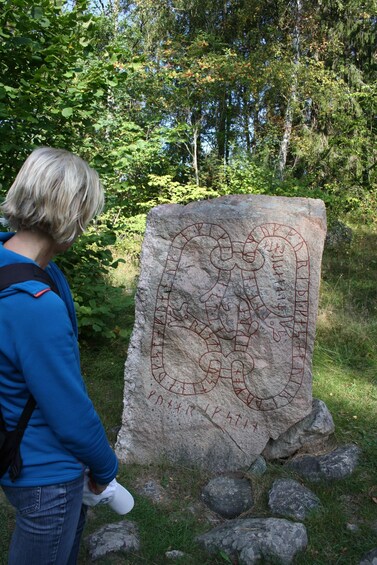 A person examining a large rock with ancient carvings. 2
