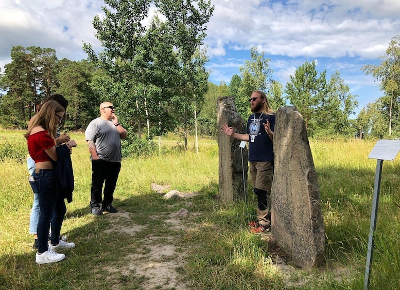 A group of people standing near a stone structure in a grassy area with trees in the background. 4
