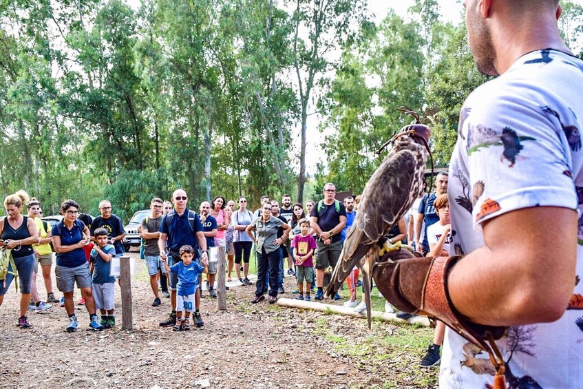 A group of people outdoors, some holding a bird. 2