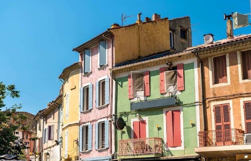 A row of colorful buildings with shutters, a balcony, and a clear blue sky. 5