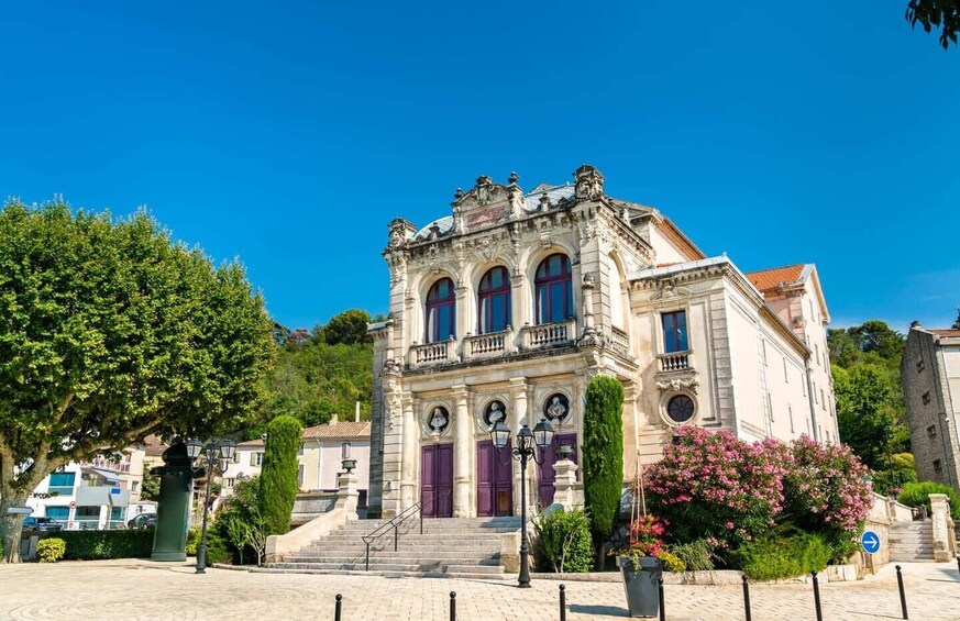 A historic building with ornate architecture, a staircase leading to the entrance, and lush greenery around. 4