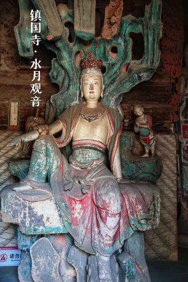 A statue of a seated figure with a crown, surrounded by a carved tree structure. 3