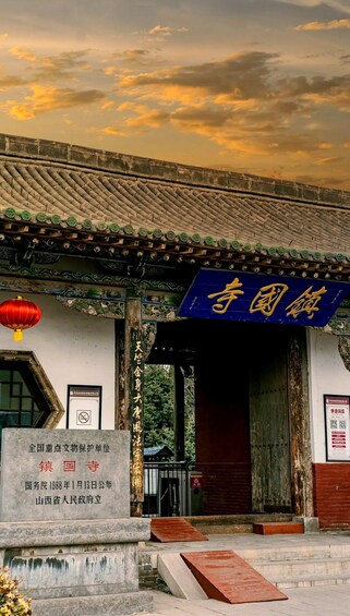 A traditional Chinese building with a blue signboard, a red lantern, and a stone plaque. 1