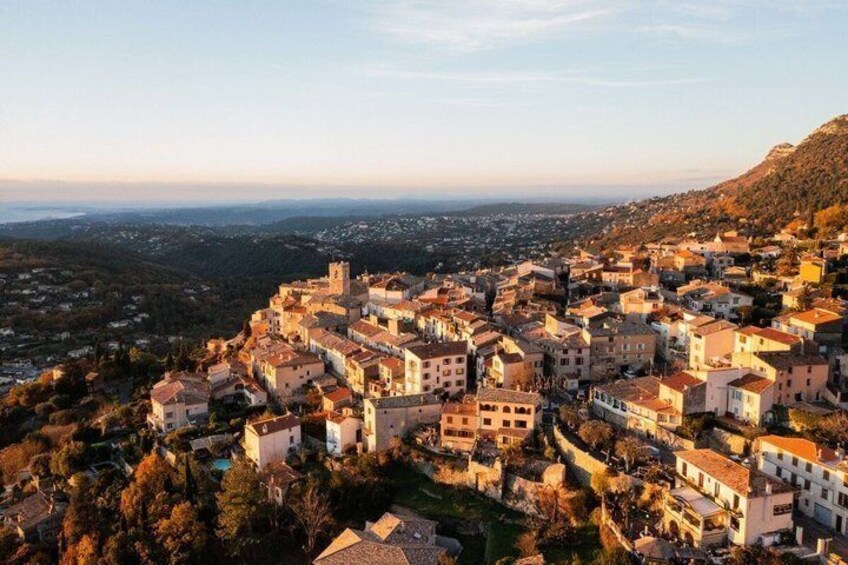 A coastal town with historic buildings, a prominent church, and a mountainous backdrop. 1