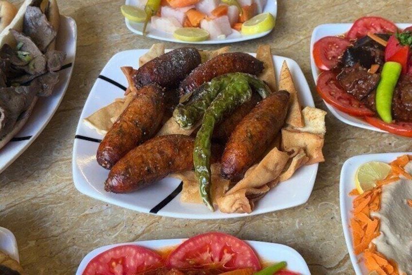 A variety of dishes including grilled sausages, vegetables, and flatbreads. 3