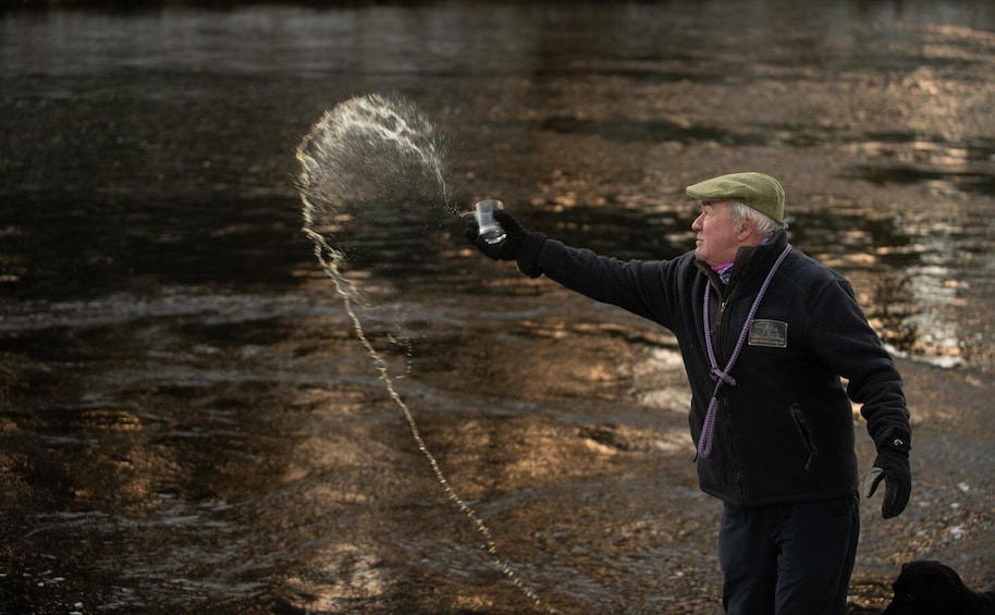 A person holding a glass with water being poured out, creating a mist. 3