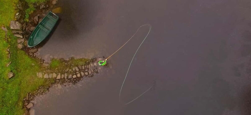 A green boat on a rocky shore, a fishing line, and a green lure. 4