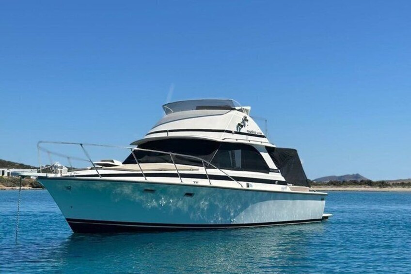 A white yacht on calm water with a clear sky. 1