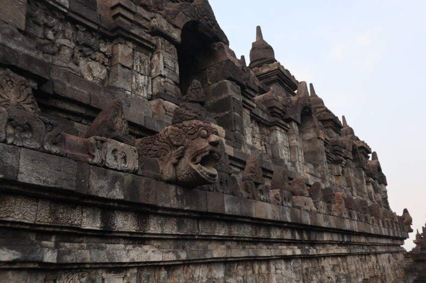 A stone temple with intricate carvings and a prominent lion head sculpture. 3