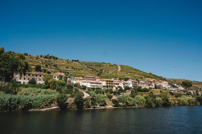 A riverside village with buildings, greenery, and a clear sky. 3