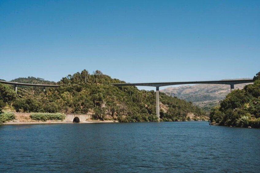 A bridge over a river with a tunnel entrance, surrounded by hills and greenery. 5