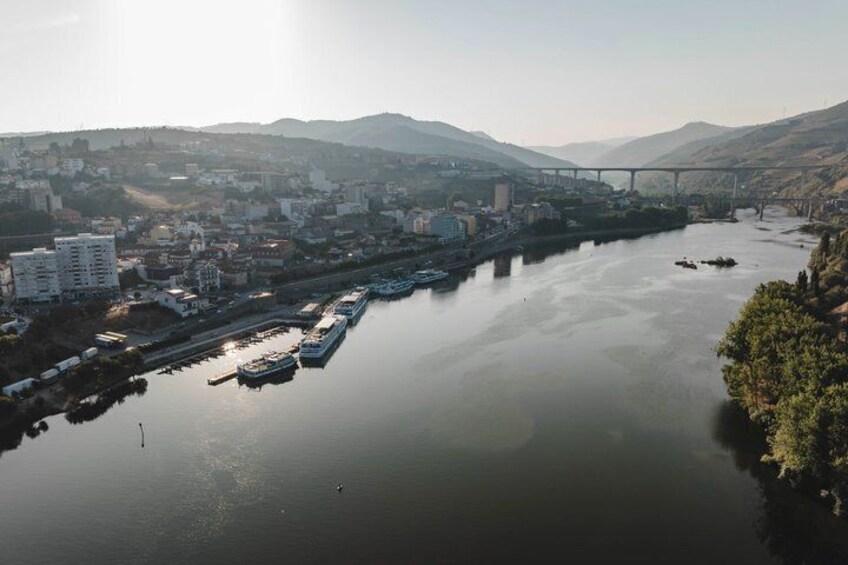 A river with boats, a bridge, buildings, and hills in the background. 2