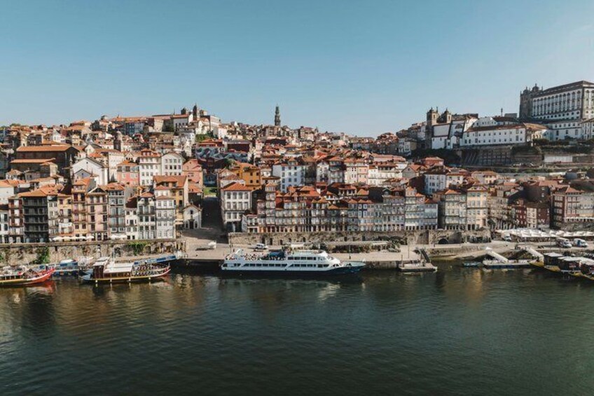 A river with boats, a cityscape with historic buildings, and a clear sky. 1