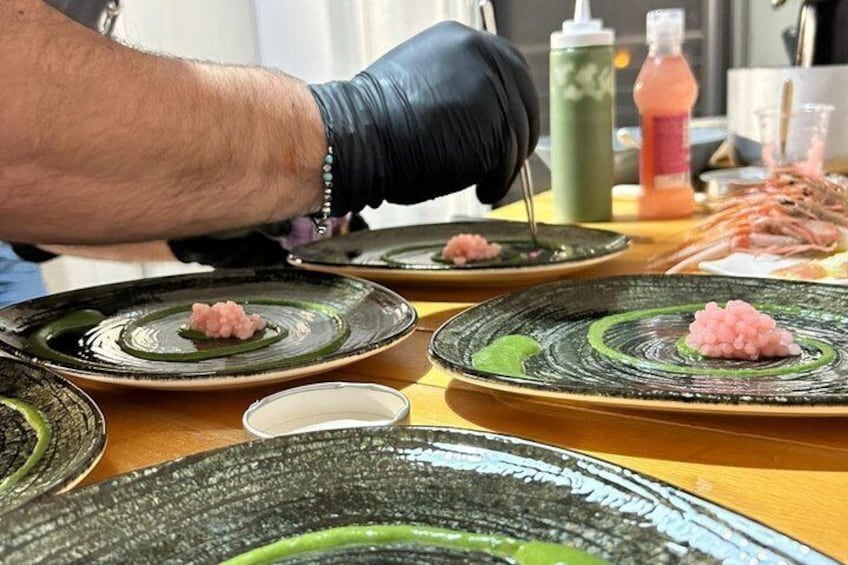 A person wearing black gloves preparing food on ceramic plates with a green glaze. 1