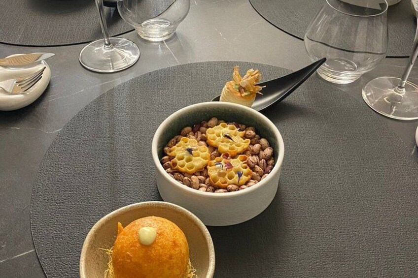 A table with a bowl of food, a spoon, and a wine glass. 4