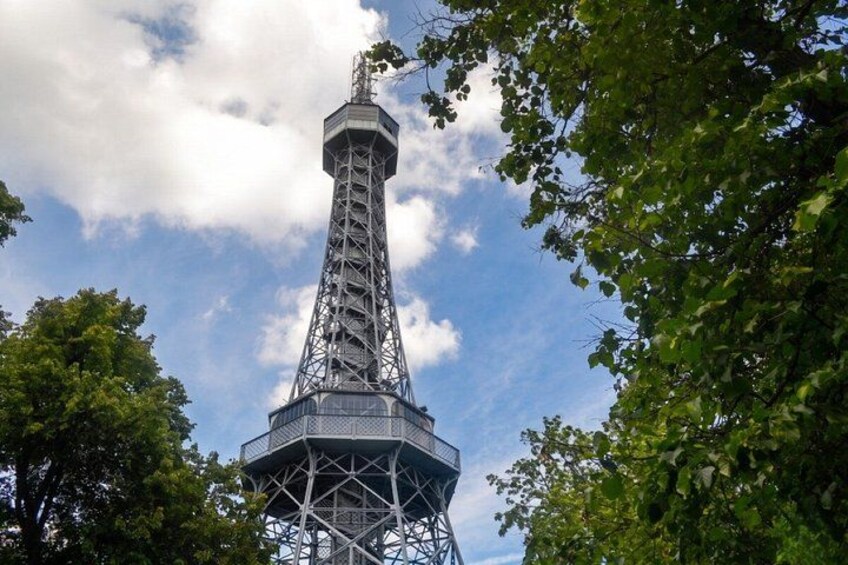 A tall, metal tower with a lattice structure, surrounded by trees and a partly cloudy sky. 1